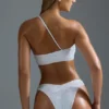 Oh Polly Moda kąpielowa: Top bikini bandeau z jednym ramiączkiem z ozdobami z serii HOTFIX w kolorze białym Oh Polly Moda kąpielowa: Top bikini bandeau z jednym ramiączkiem z ozdobami z serii HOTFIX w kolorze białym